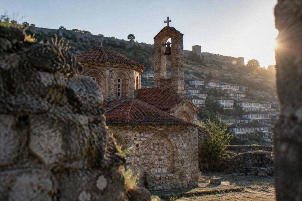 Whitewashed houses climbing the hillside toward Berat Castle on a clear day