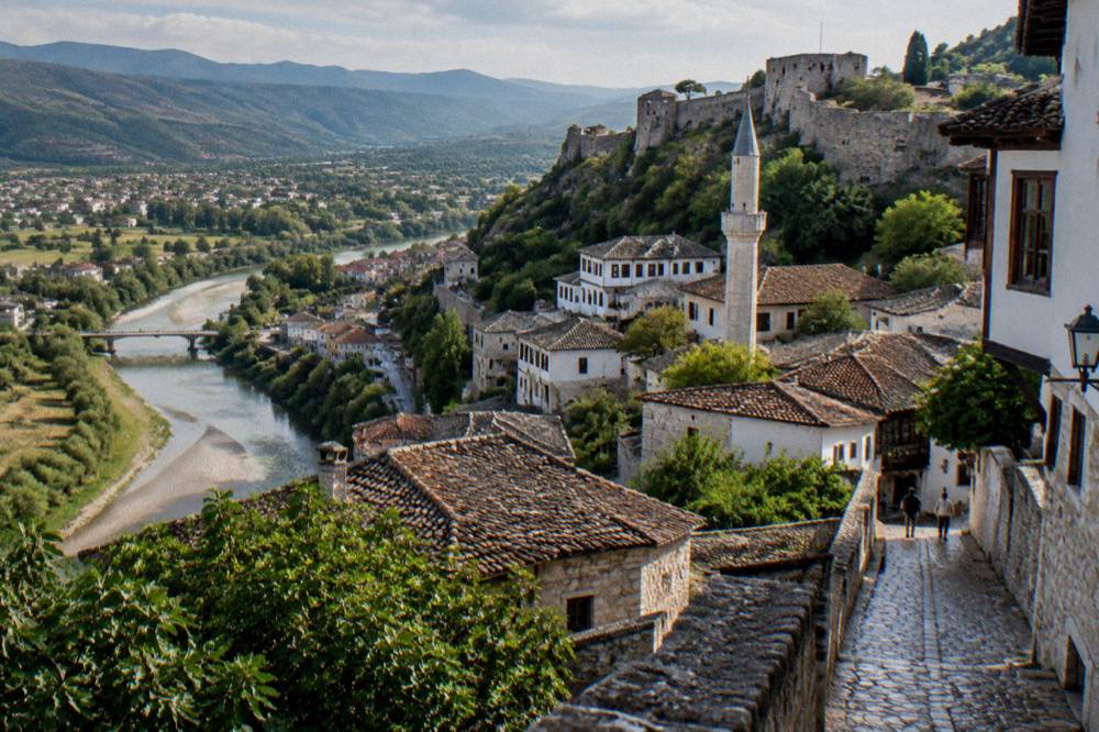 A minaret rising among old stone buildings on a street in central Berat