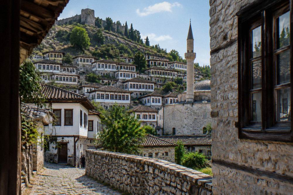 Stone minaret and mosque wall rising above the whitewashed Ottoman houses of Mangalem in Berat