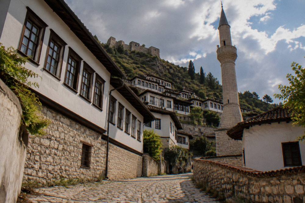 Cobbled lane in Mangalem with the stone base of a minaret and the hillside of Berat behind