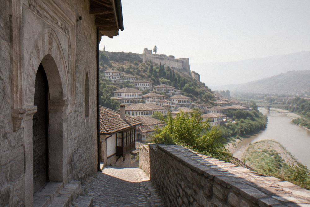 Carved stone doorway and shaded wall of an old mosque in Berat seen from a narrow lane