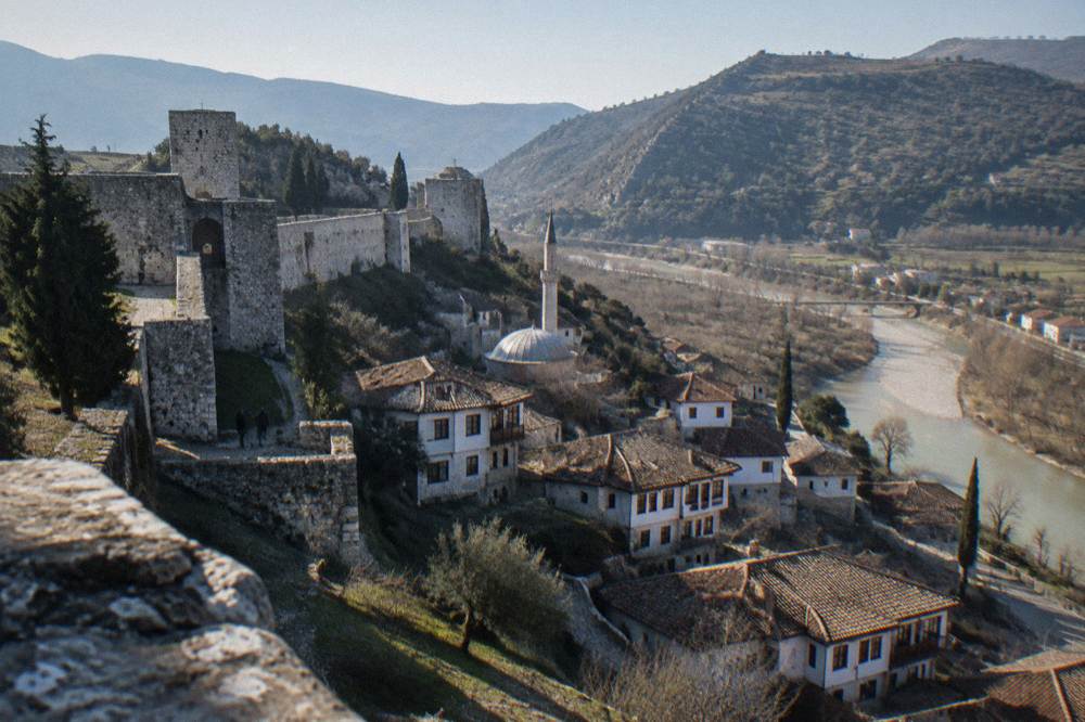 Small Ottoman mosque with a low lead-covered dome rising among stone houses on a hillside in Berat