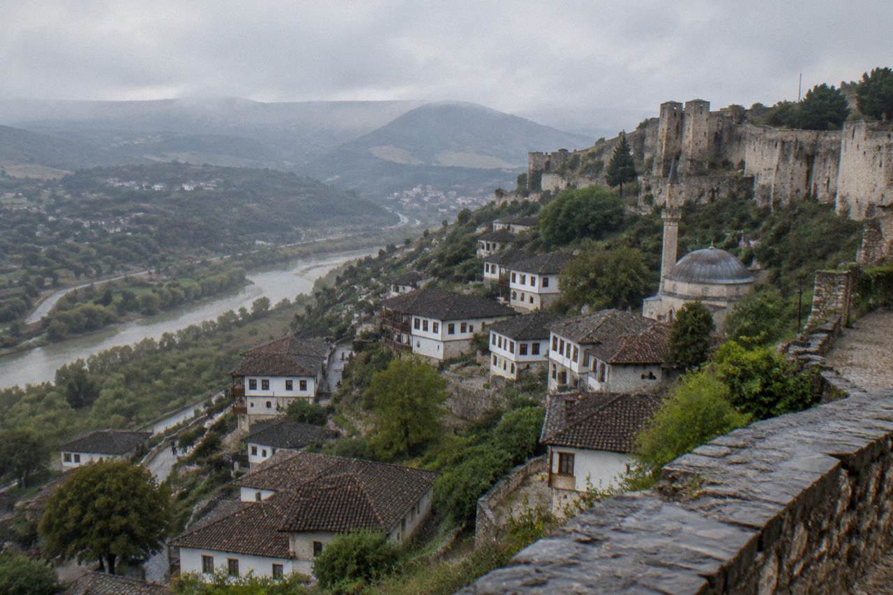 Small Ottoman mosque with a low lead-covered dome rising among stone houses on a hillside in Berat