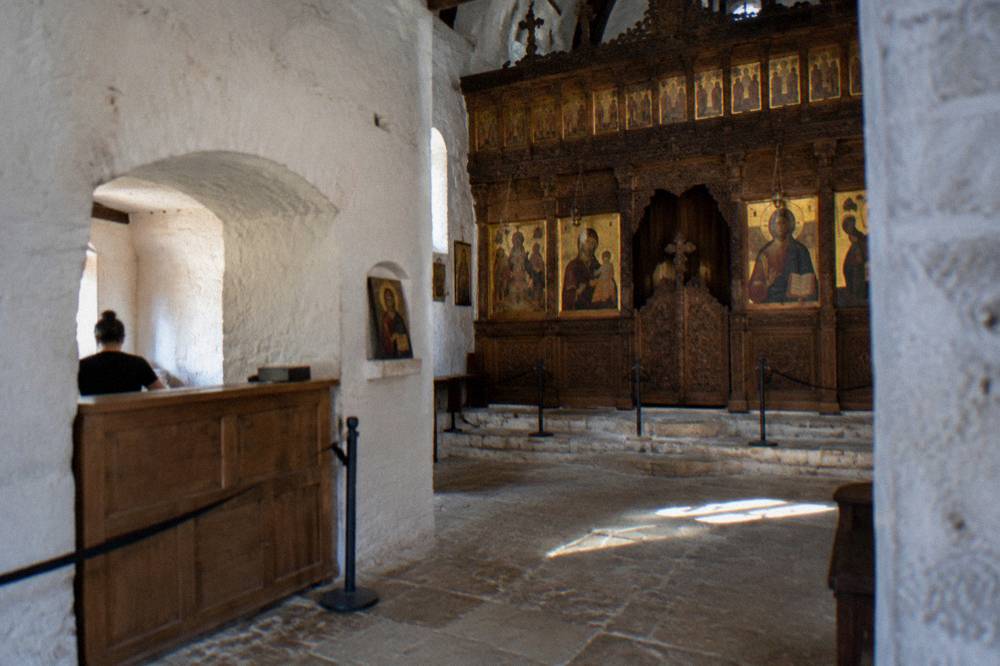 Museum ticket desk in a whitewashed church porch with a wooden sign and stone archway