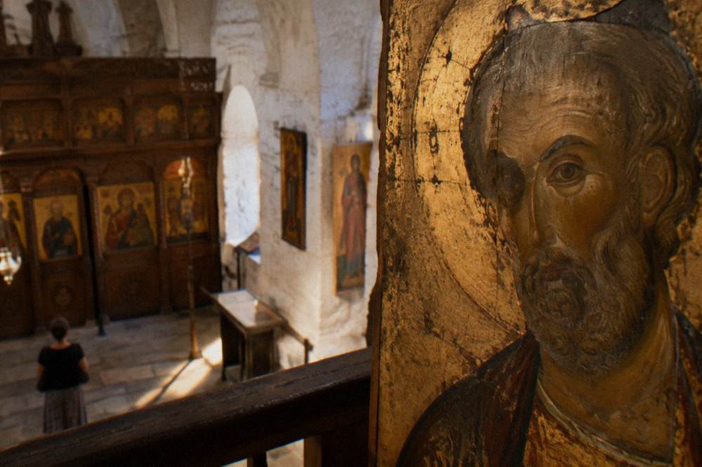 Close view of a gilded icon panel showing a saint's face painted on aged wood