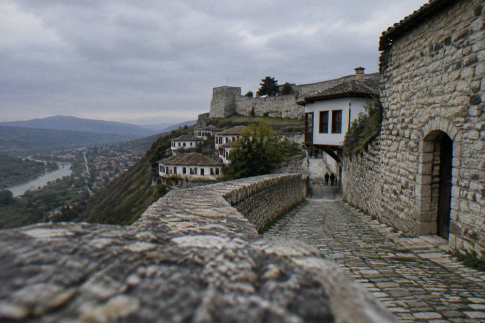 Cobbled lane inside Berat Castle passing old stone walls and low doorways