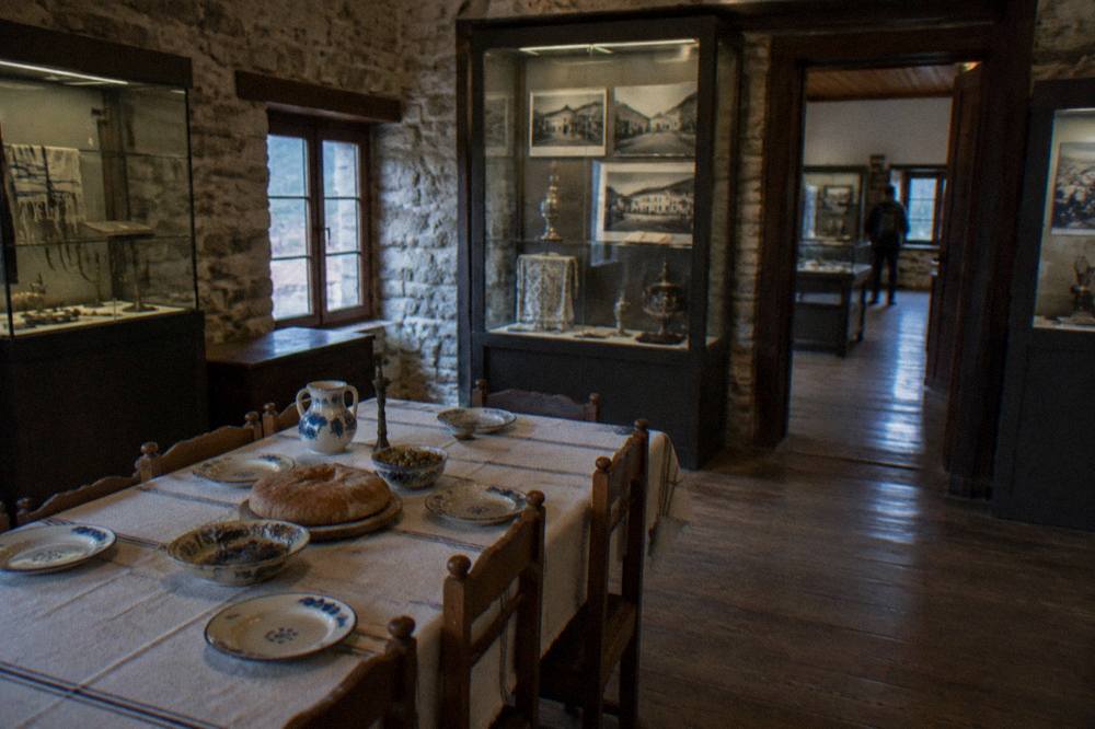 A traditional dining table set with ceramic dishes and bread in a stone-walled room