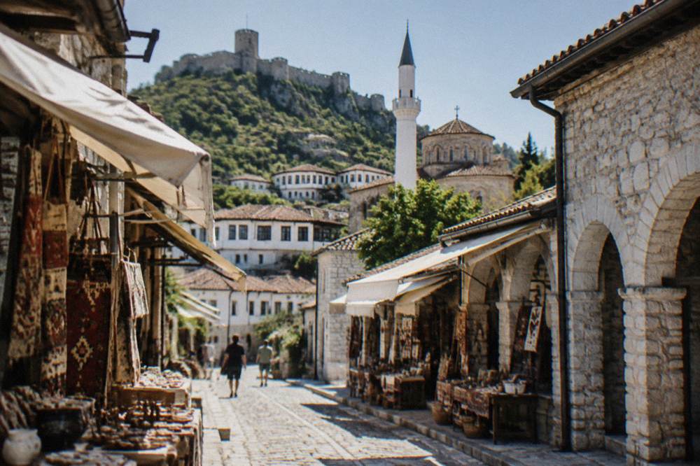 Whitewashed mosque minaret rising beside church rooftops in the Berat old town