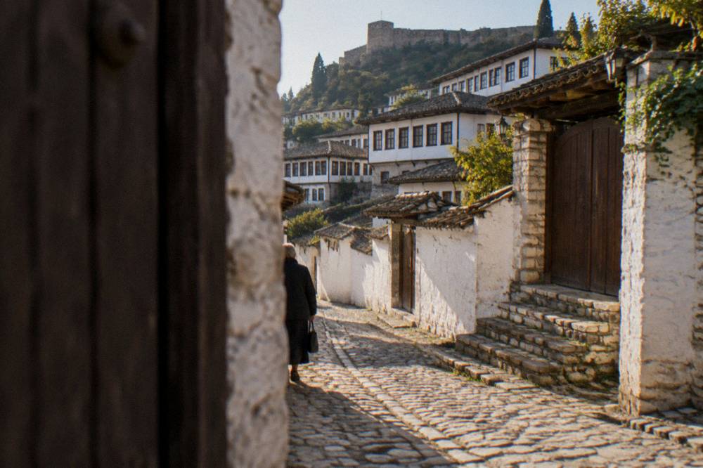Cobbled lane in Mangalem with wooden gates, stone steps and whitewashed walls in morning light