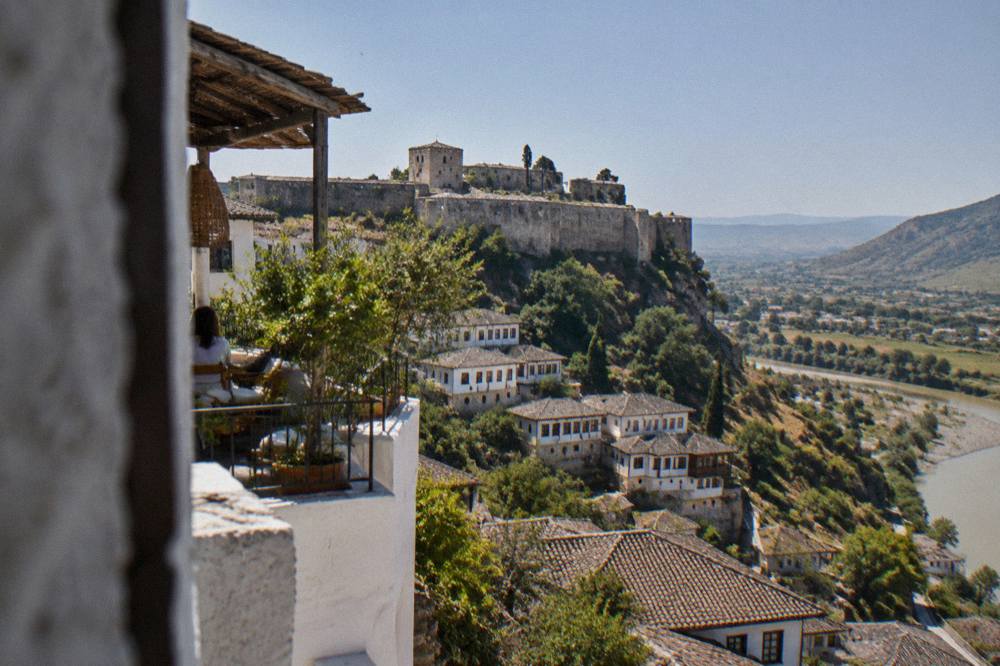 Whitewashed guesthouse terraces stacked on the hillside of Berat above the Osum River