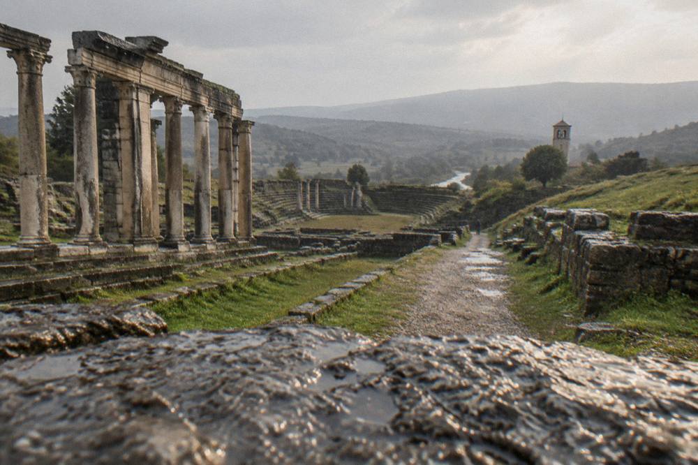 A quiet path between ancient stone terraces leading toward a distant bell tower
