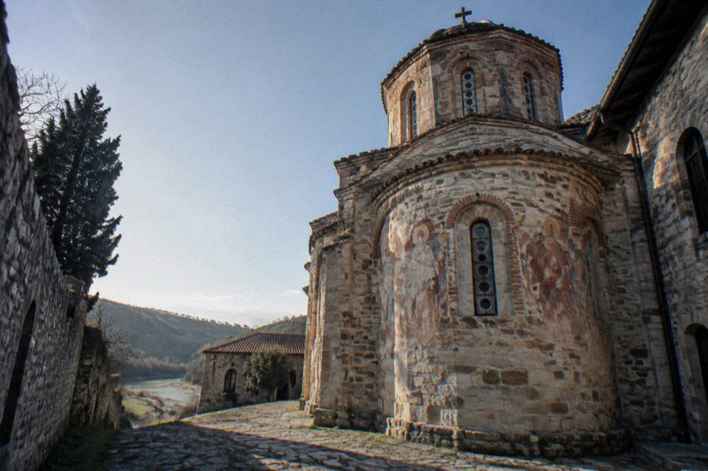 A stone church facade with a small dome and arched windows lit by afternoon sun