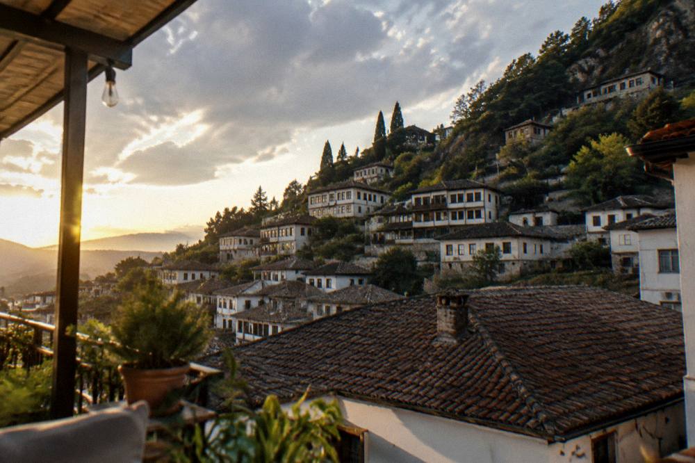 A guesthouse terrace above the tiled roofs of Gorica quarter in Berat at golden hour