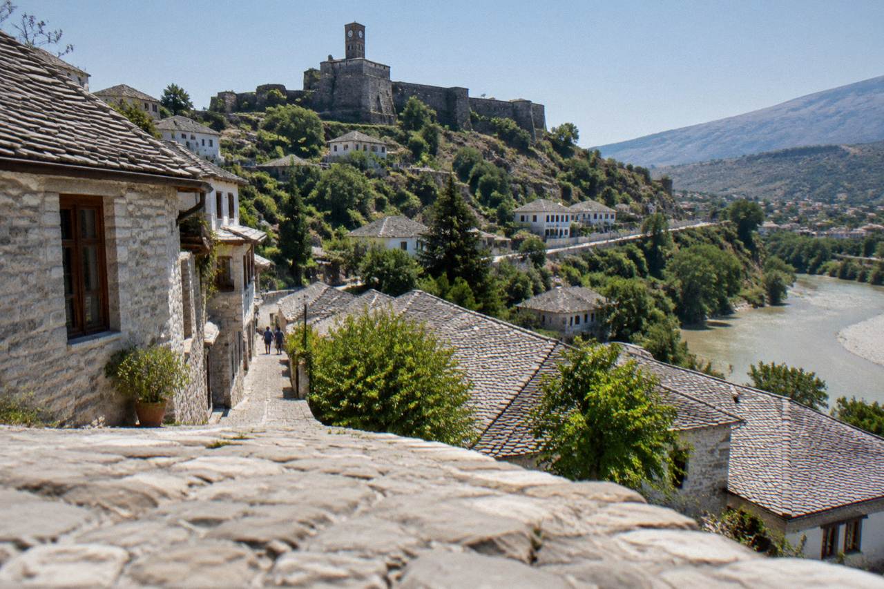 Stone houses with grey slate roofs climbing a steep hillside under a clear sky