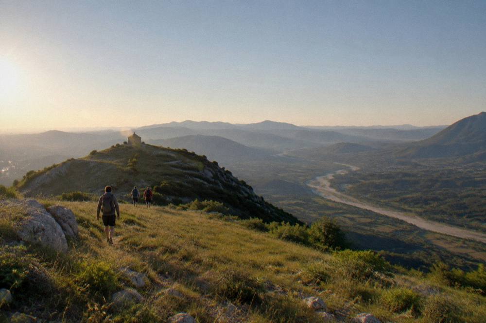 An open grassy hiking ridge on Mount Tomorr with wide views over the Osum valley