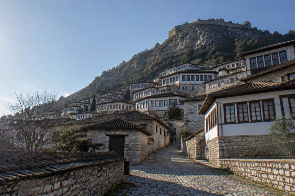Traditional stone houses of the Mangalem quarter stacked on the hillside with the mountain behind