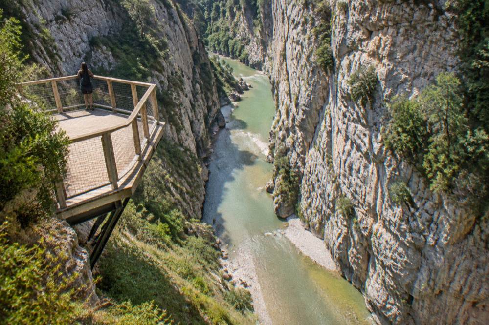 Steep pale cliffs of Osumi Canyon above calm turquoise river water