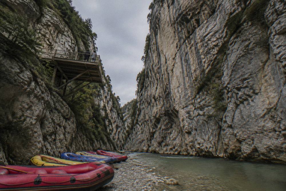 Inflatable rafts lined up on a gravel riverbank beside Osumi Canyon