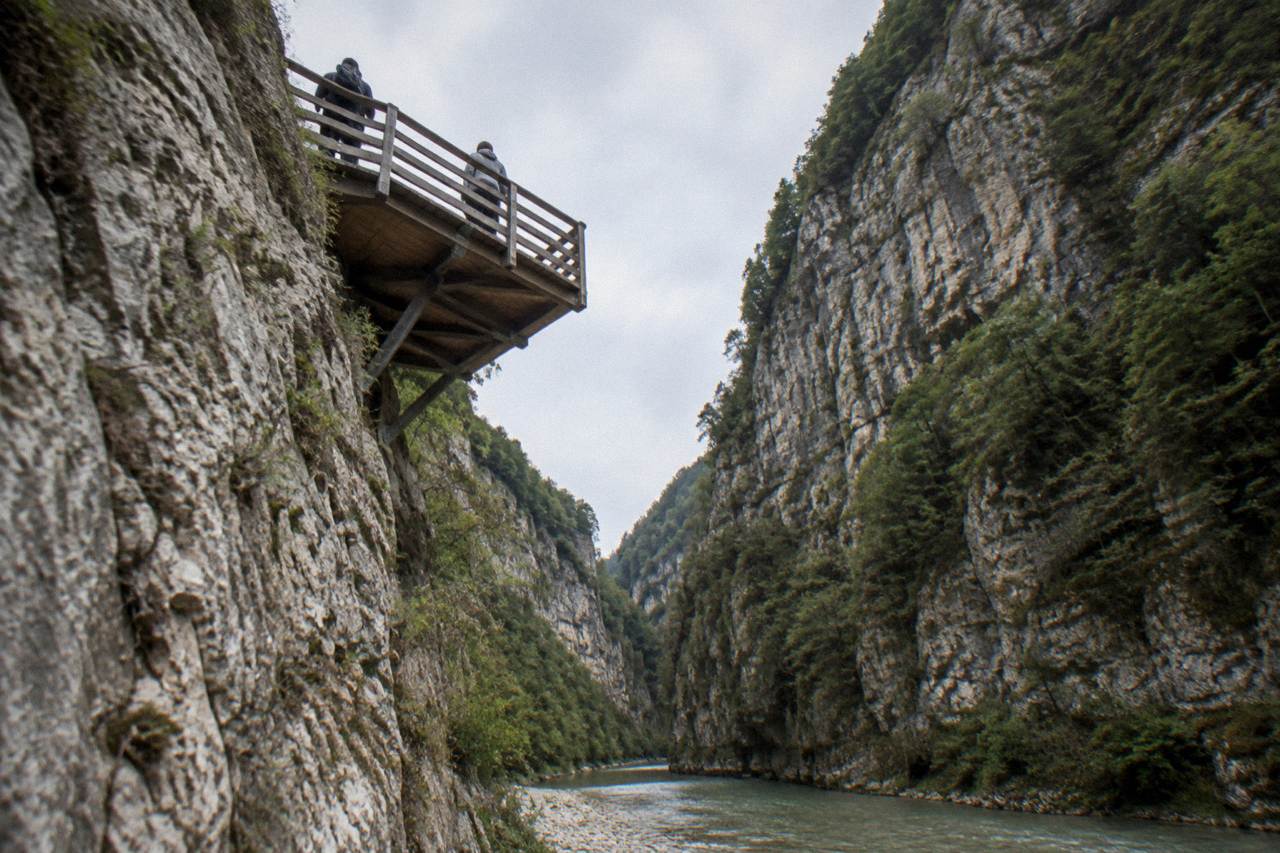 A deep limestone river gorge with steep forested walls and green water running along the canyon floor