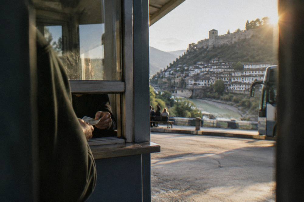 A simple ticket window at a bus terminal with a hand passing banknotes to a clerk through the opening