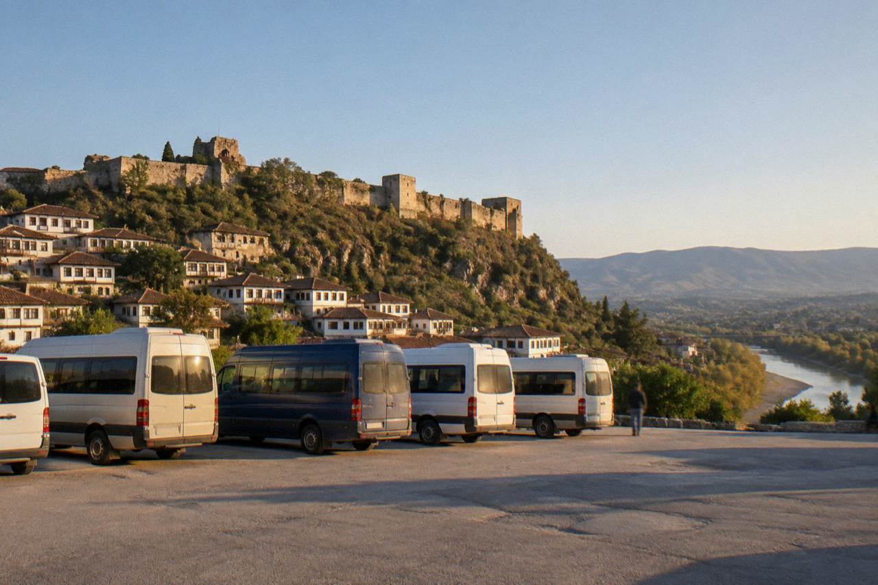 A small regional bus terminal forecourt with several minibuses parked in a row under a clear morning sky