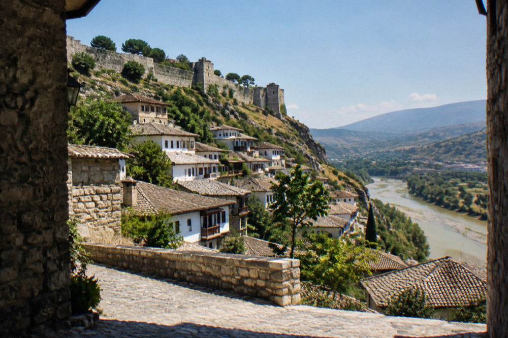 White Ottoman houses stacked on a hillside above a river in Berat, Albania
