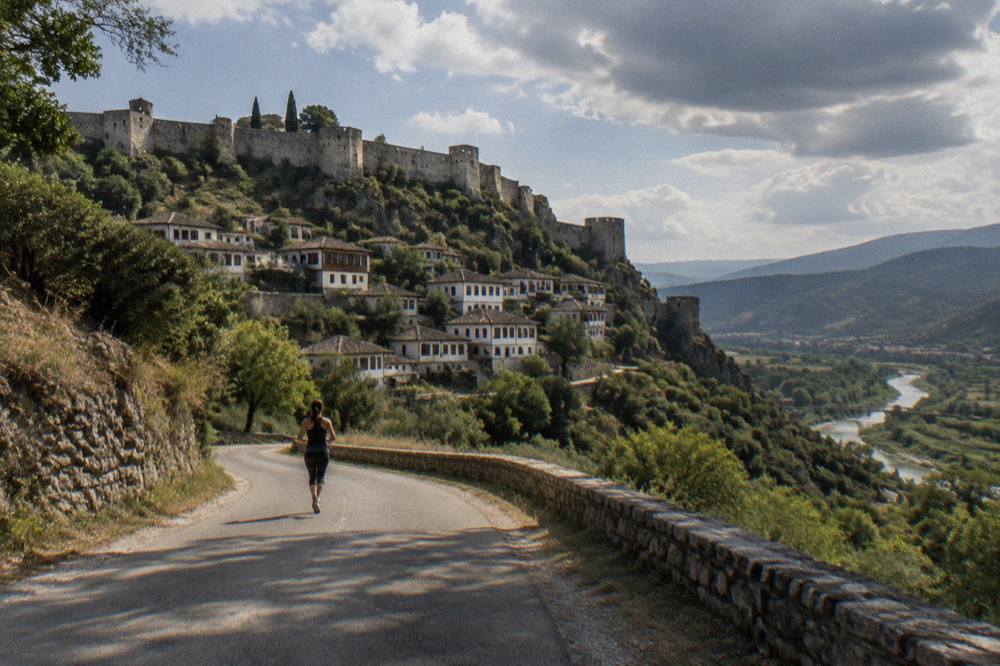 A country road winding through green hills toward the town of Berat
