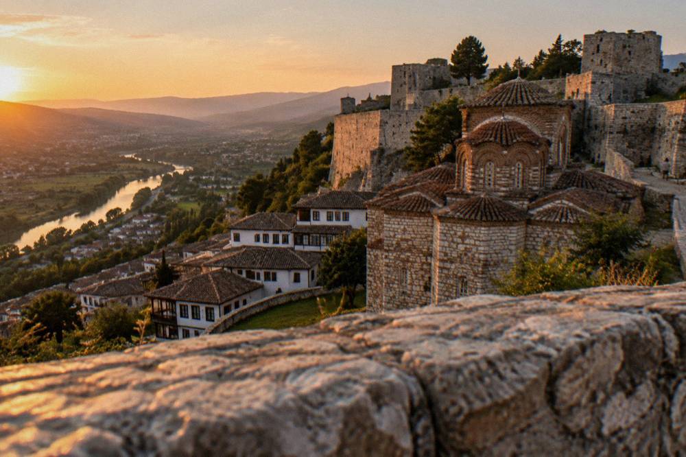 A stone fortress wall and old church rooftops inside Berat Castle in Albania
