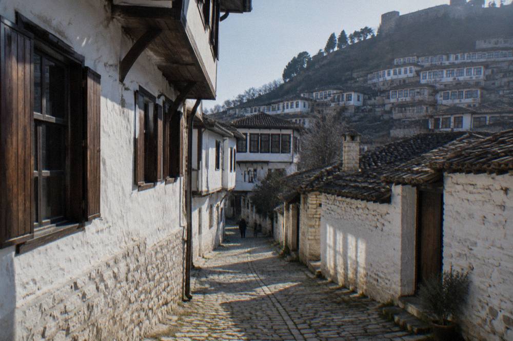 A narrow cobbled lane in Mangalem with whitewashed houses and wooden window shutters