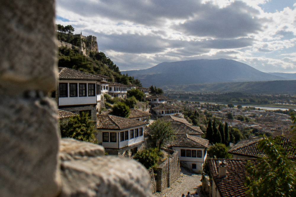 A view over Berat's rooftops from the castle walls toward Mount Tomorr in the distance