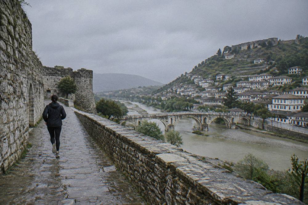A stone bridge crossing the Osum River with Berat's hillside houses rising behind it