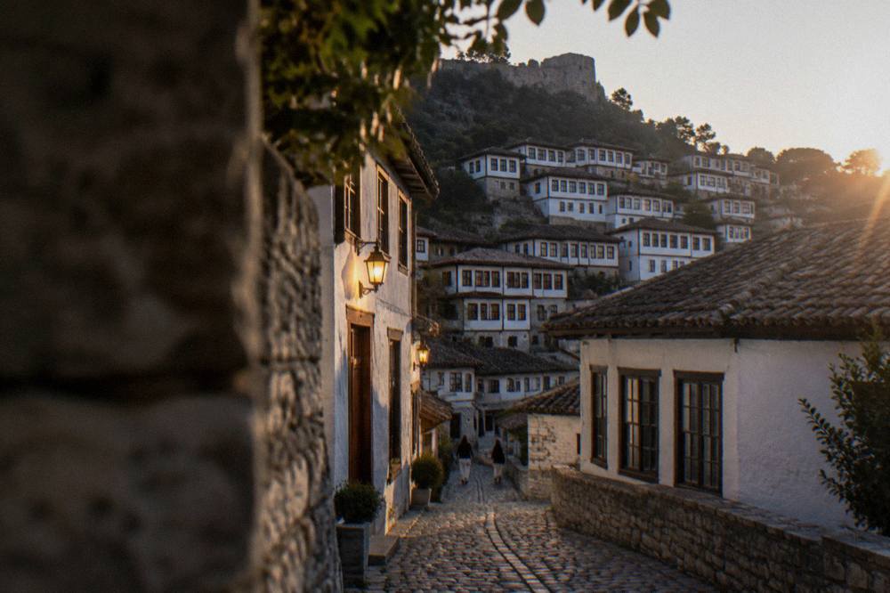 Cobbled lane in Mangalem with warm lamps glowing on white Ottoman walls in Berat, Albania