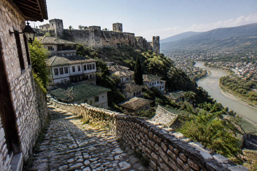 Empty cobbled street in Berat at night with warm lamps reflecting on stone walls, Albania