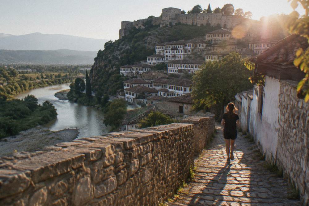 White Ottoman houses stacked on a hillside above a river in Berat Albania