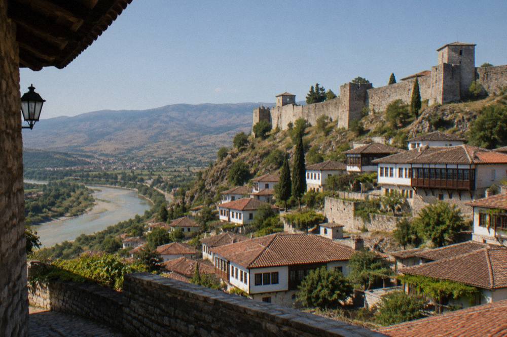 Stone castle walls and towers on a hill above red tiled roofs in Berat