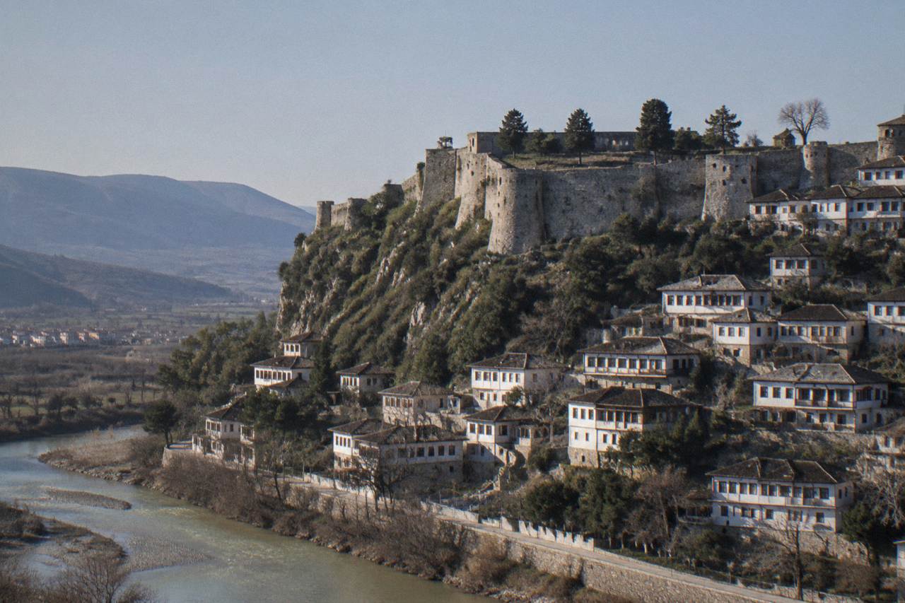 White Ottoman houses stacked on a hillside above a river in Berat Albania