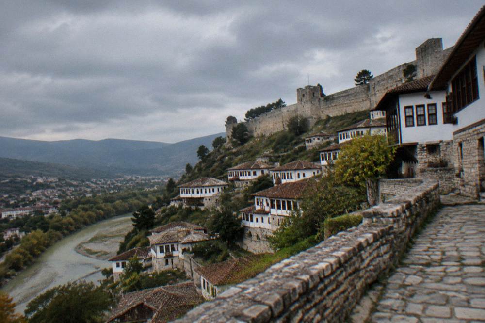White Ottoman houses stacked on a hillside above a river in a Balkan town