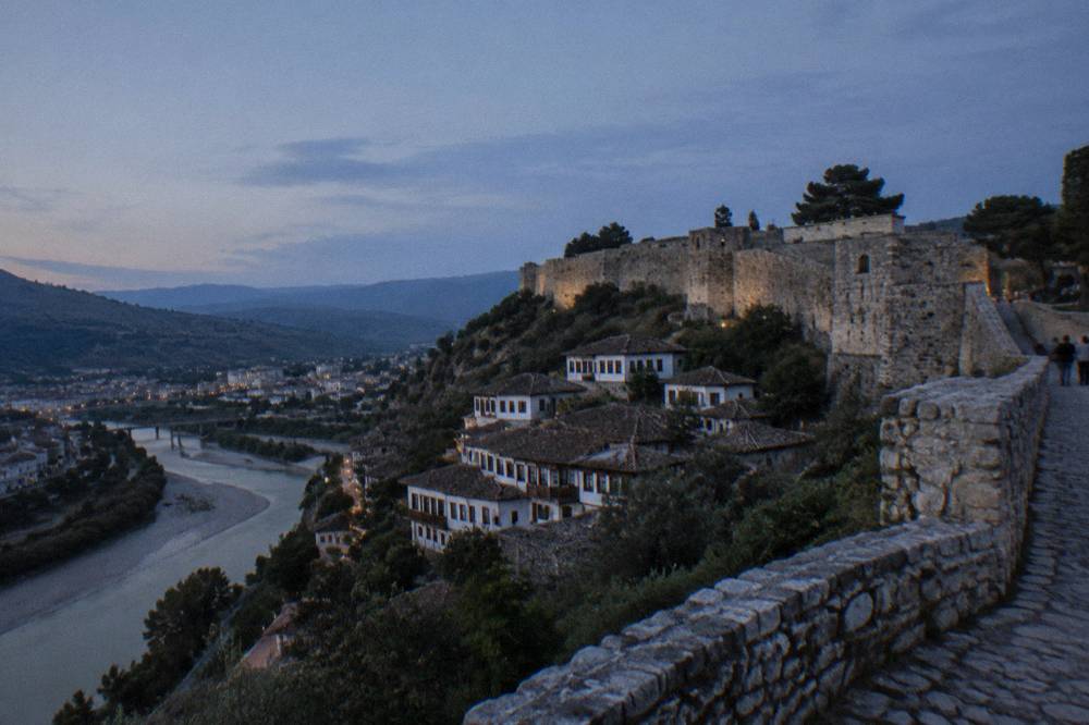 Stone castle walls and towers on a hill above a river town
