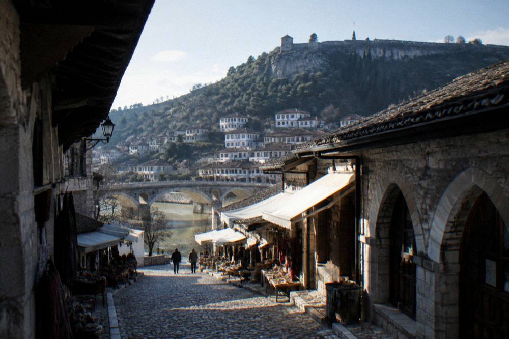 Evening view over tiled roofs of an old town with a lit bridge