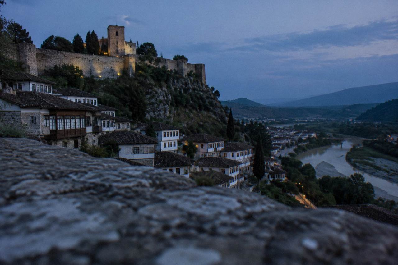 White Ottoman houses stacked on a hillside above a river in a Balkan town