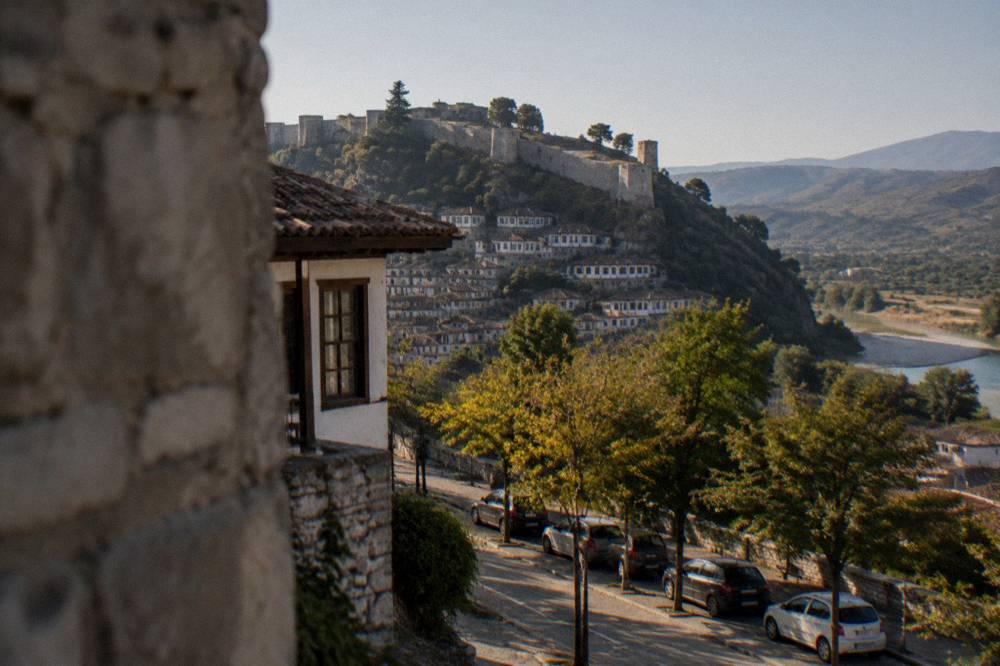Row of parked cars along a tree-lined boulevard in the newer part of Berat