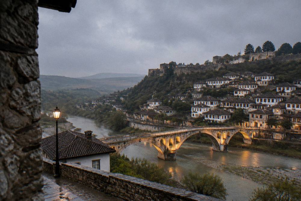 Illuminated stone bridge over the Osum River linking the two old quarters of Berat at dusk