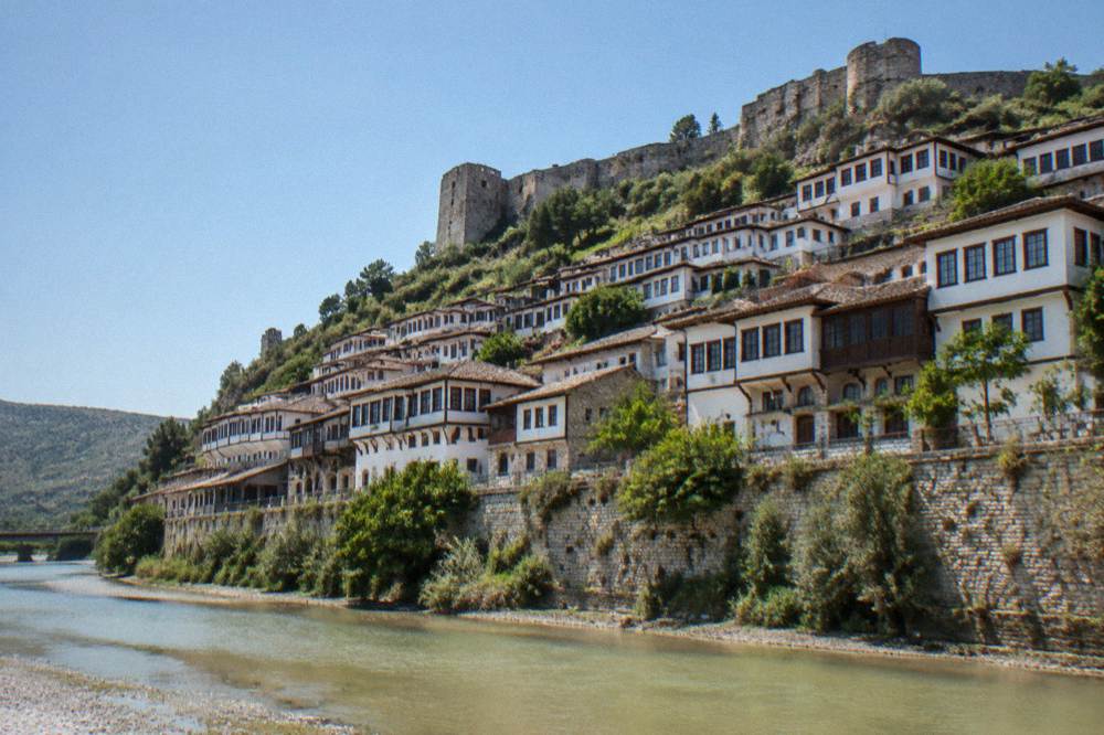 Steep hillside of white Ottoman houses with rows of windows above the Osum River in Berat