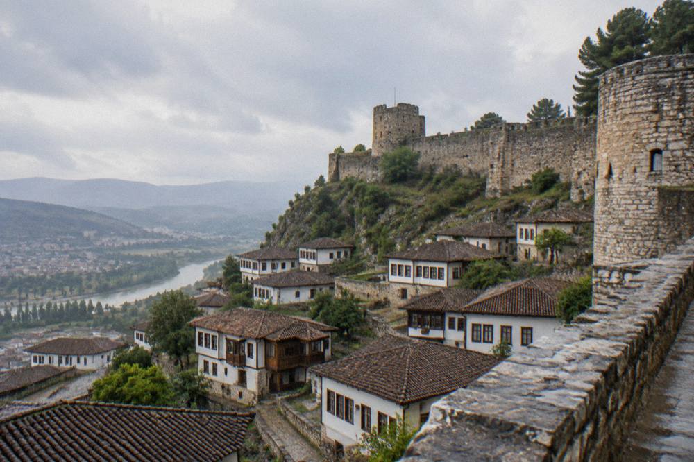 Stone fortress walls and round towers of Berat Castle above the town at midday