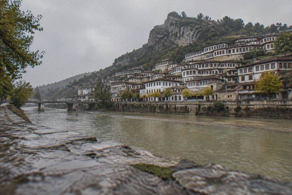 View across the Osum River to the stacked white houses of Mangalem from the Gorica bank