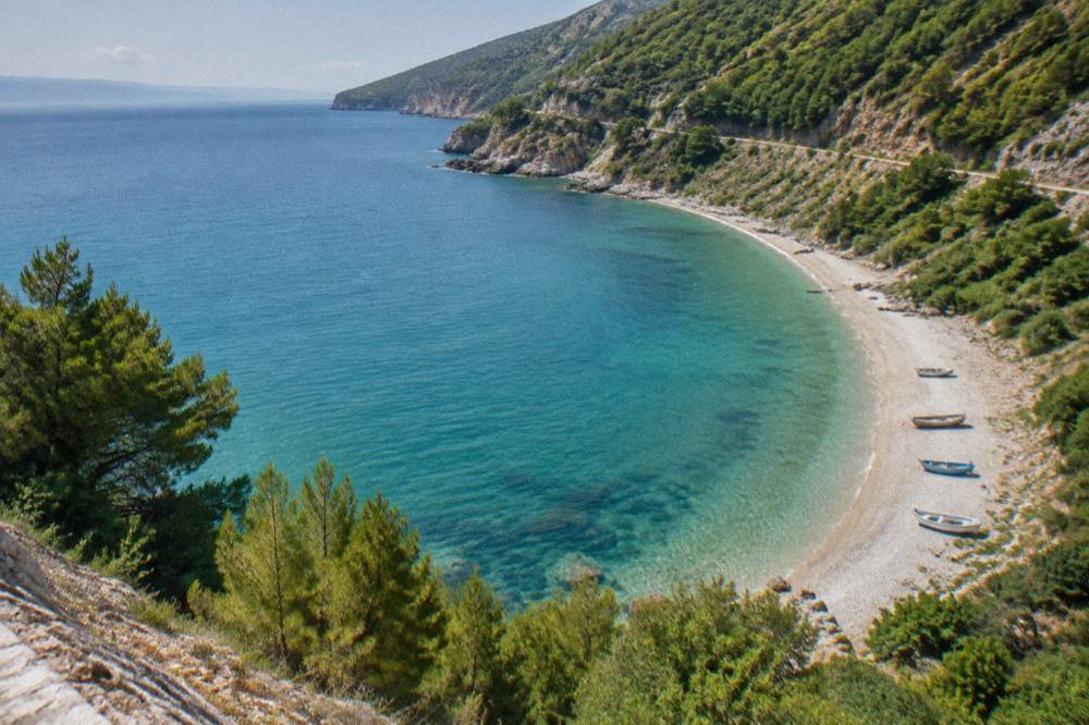 Turquoise sea seen from a high coastal road with pine covered slopes