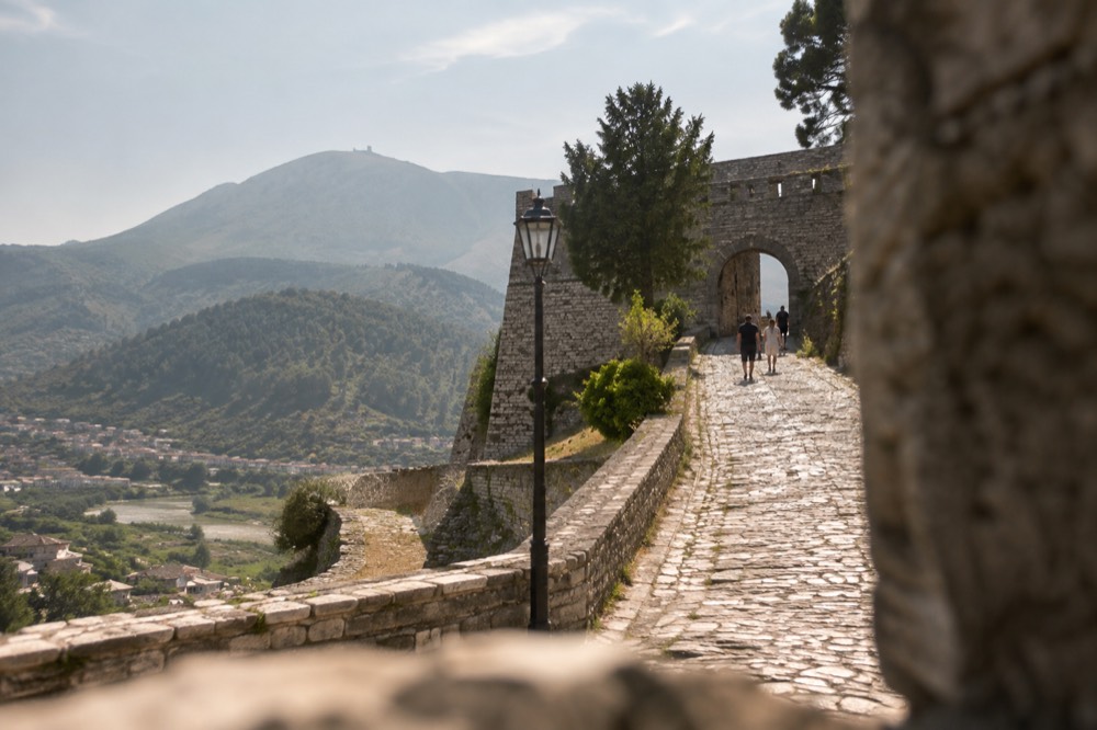 Cobbled lane climbing toward the entrance gate of Berat Castle