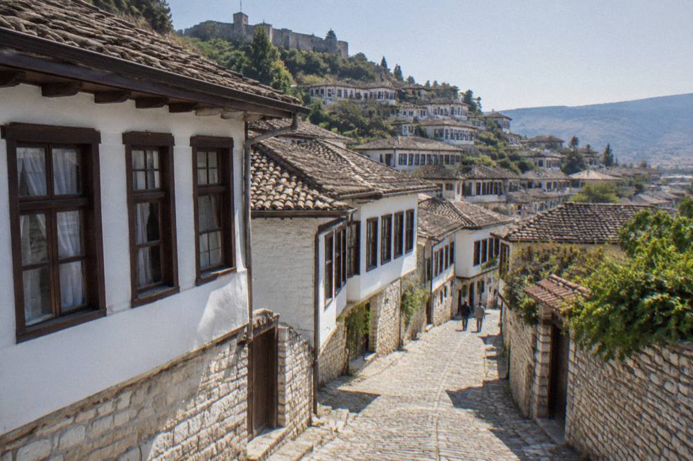 Cobbled stone lane with whitewashed houses and wooden windows in Mangalem, Berat