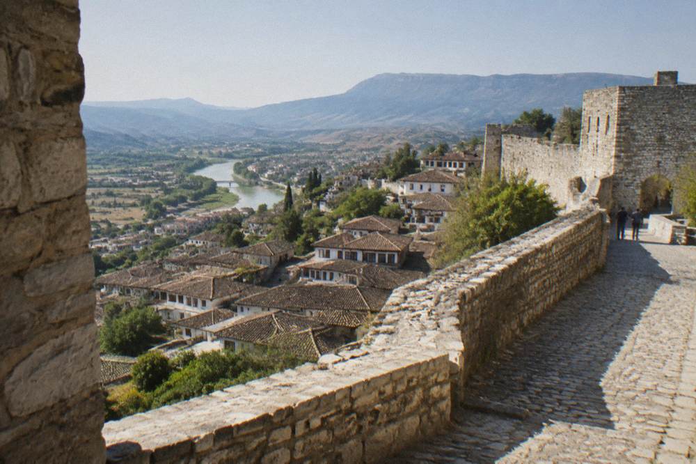 Stone fortress walls and a cobbled path inside Berat Castle above the town