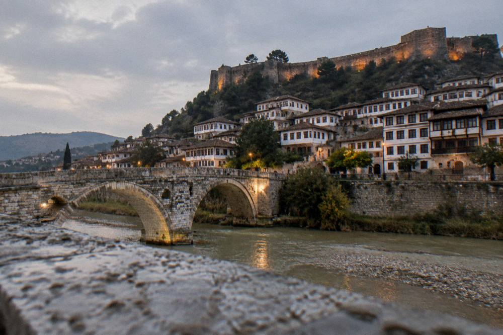 Stoned bridge over the Osum River with hillside houses at dusk in Berat